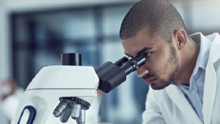 Man looking down microscope 