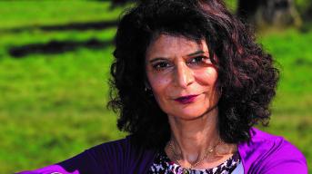 Middle aged woman in a purple cardigan looking at the camera