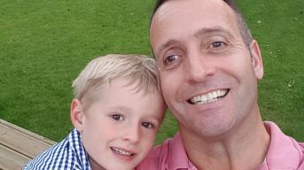 Middle aged man in a pink shirt and a young boy taking a selfie smiling at the camera