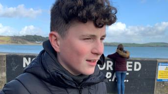 Young boy near the sea looking past the camera