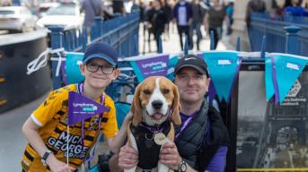 Man and boy holding Lymphoma Action flag with dog wearing a medal