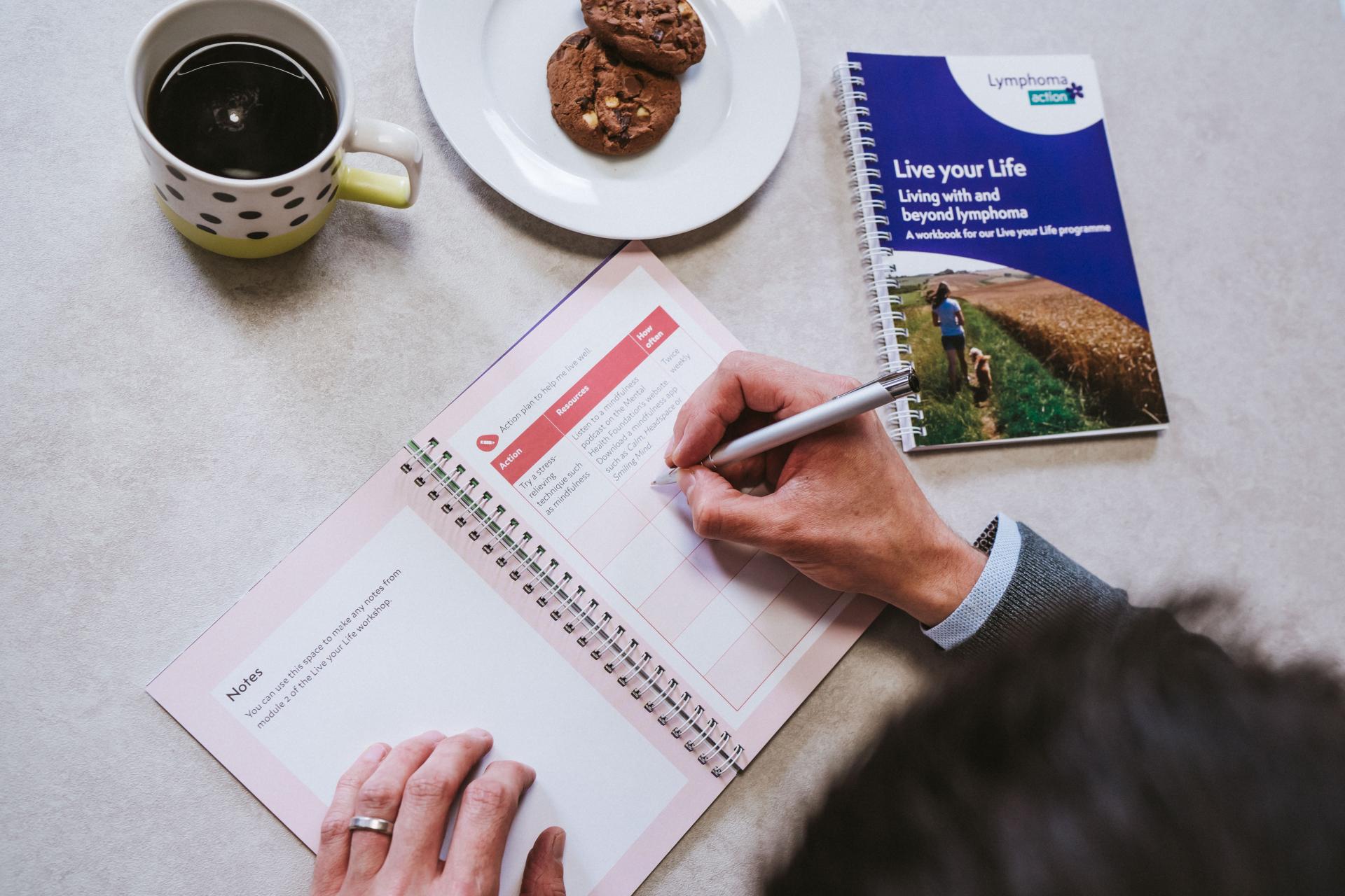 Close up image of a person writing in a Live your Life workbook.
