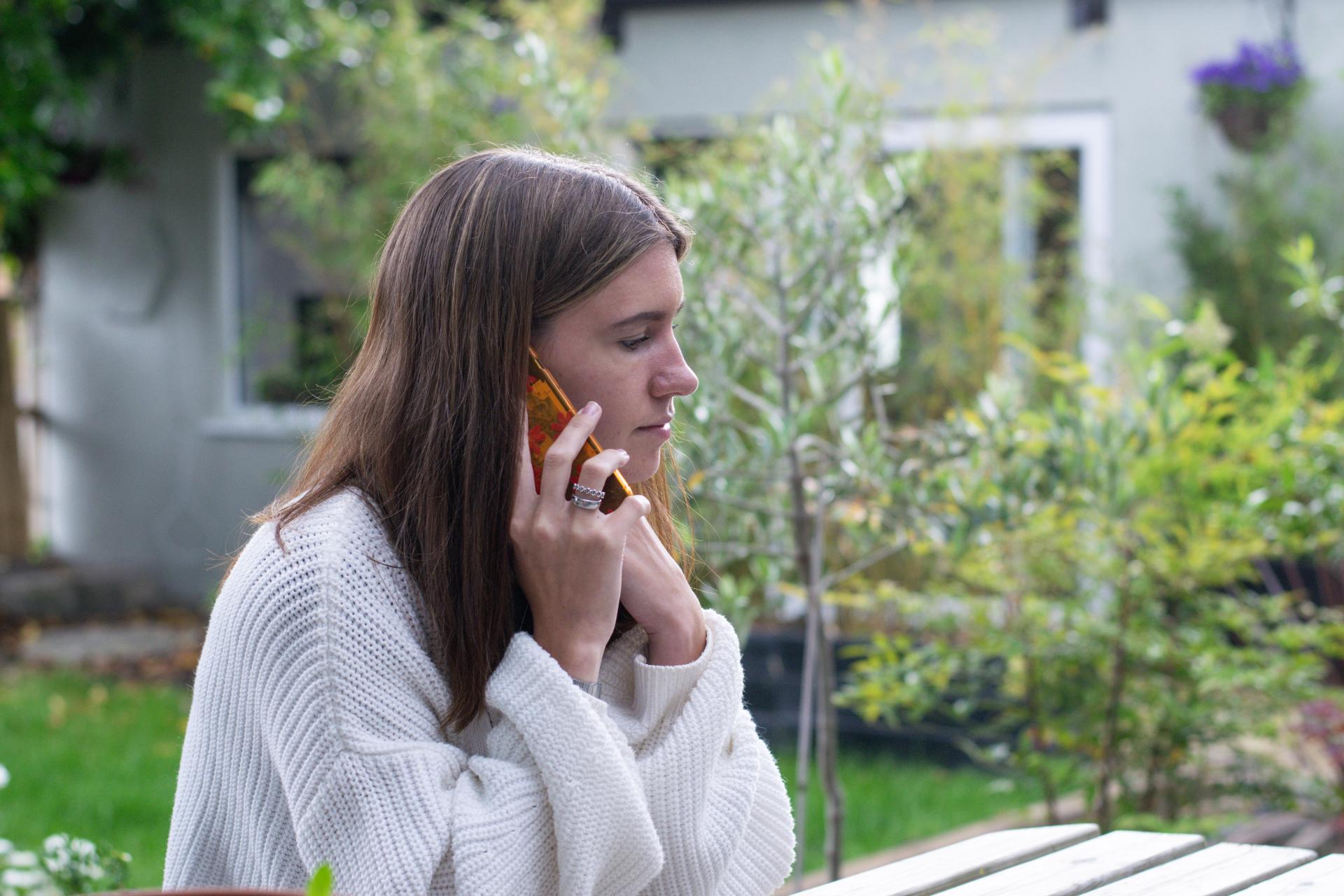 Young woman listening to a mobile phone call outside in a calm garden