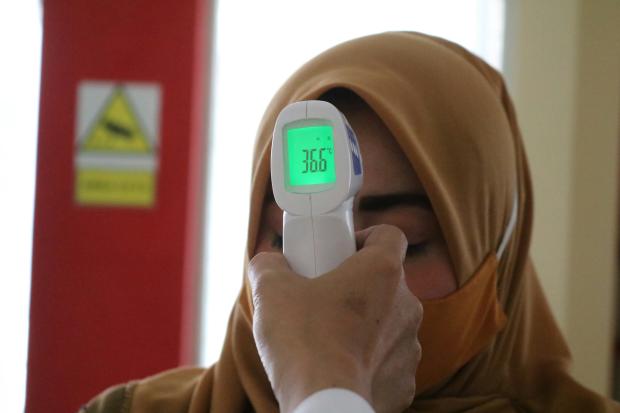 Photo of a woman having her temperature checked