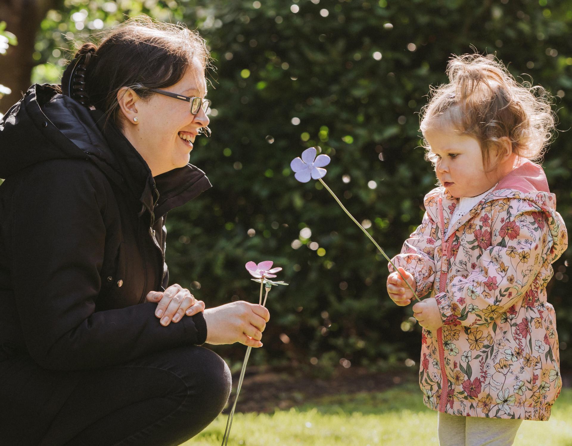 Mother and daughter looking at each other with flower in hand