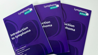 A fan shape of three 'What is lymphoma' books all with purple covers