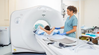 A doctor standing next to a patient who is having a CT scan