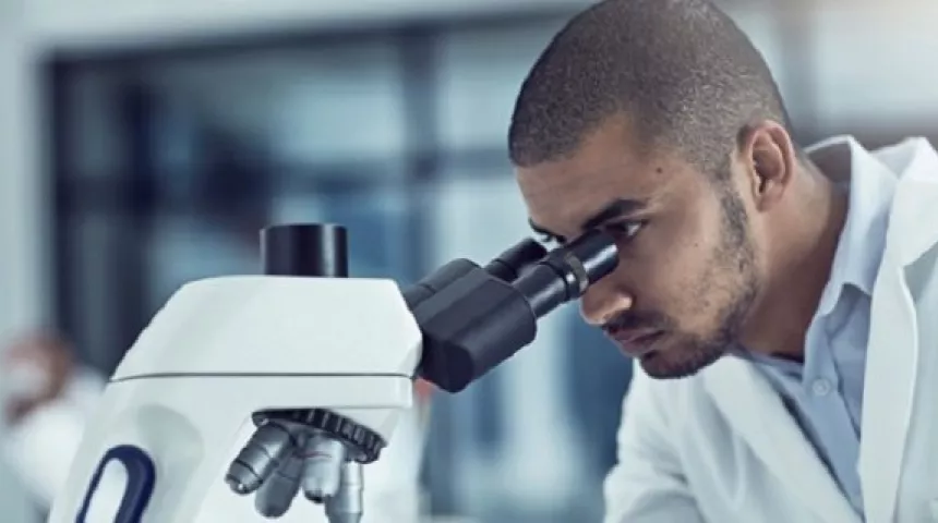 Man looking down microscope 