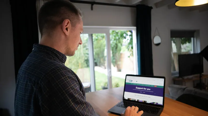 Man stood looking at laptop screen that says 'Support for you'