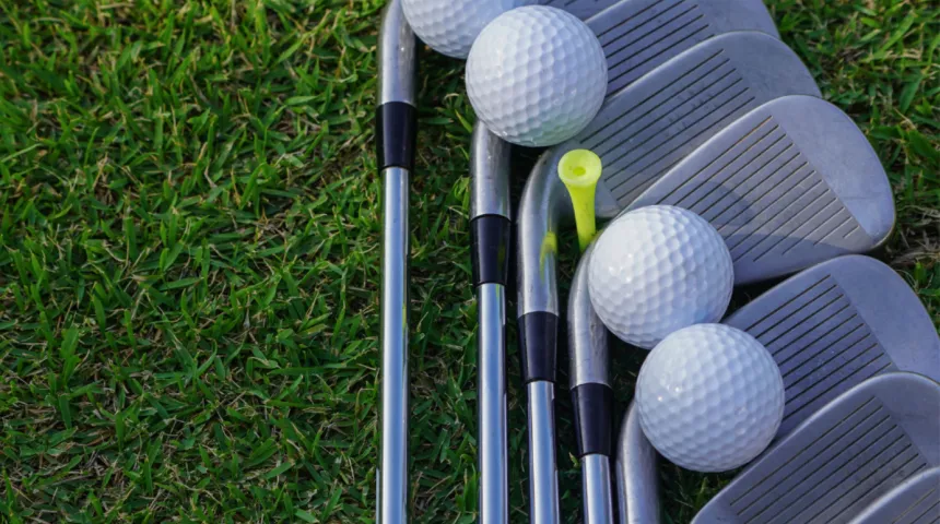 7 golf clubs and golf balls laying on grass 