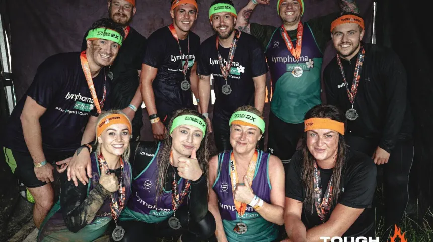 10 Tough mudder runners in their finnishers medals covered in mud 