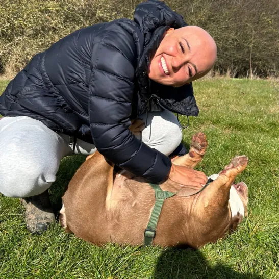 Molly smiling at the camera while petting a dog