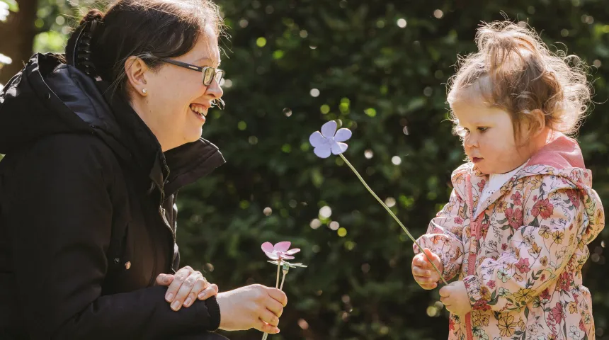 Mother and daughter looking at each other with flower in hand