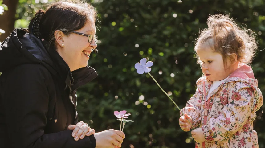 Mother and daughter looking at each other with flower in hand