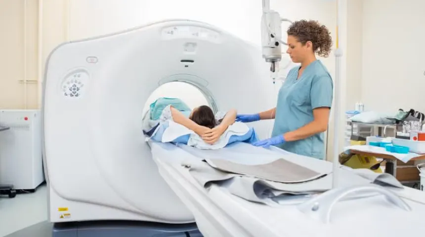 A doctor standing next to a patient who is having a CT scan