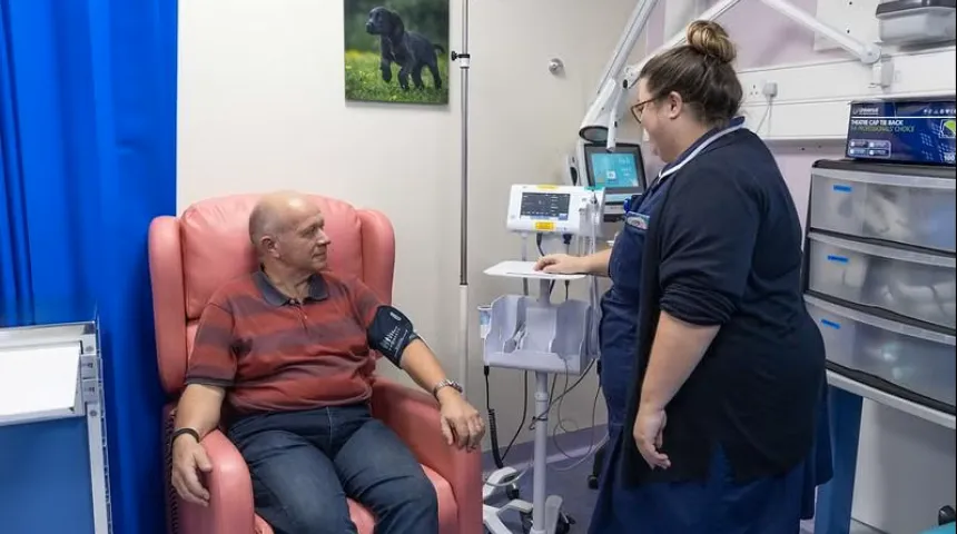 A man sat in a clinic room having treatment with a nurse