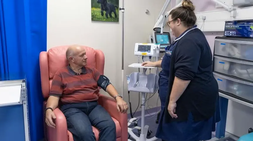 A man sat in a clinic room having treatment with a nurse