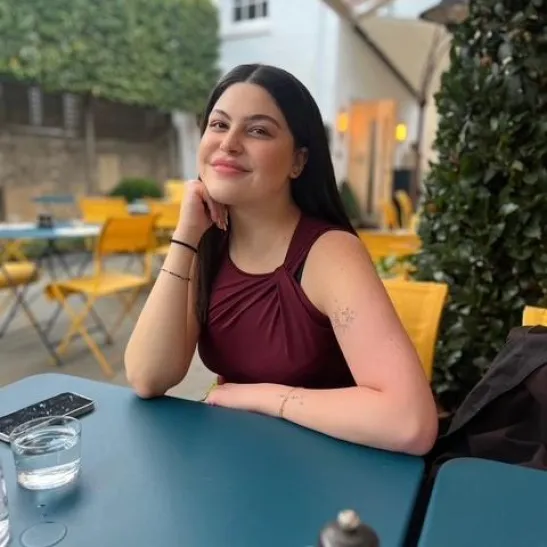 Batoul seated in an outdoor area of a restaurant. She is smiling at the camera. 